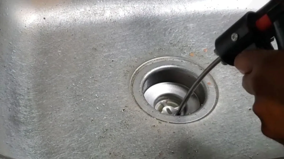 Drain cable entering a sink drain opening