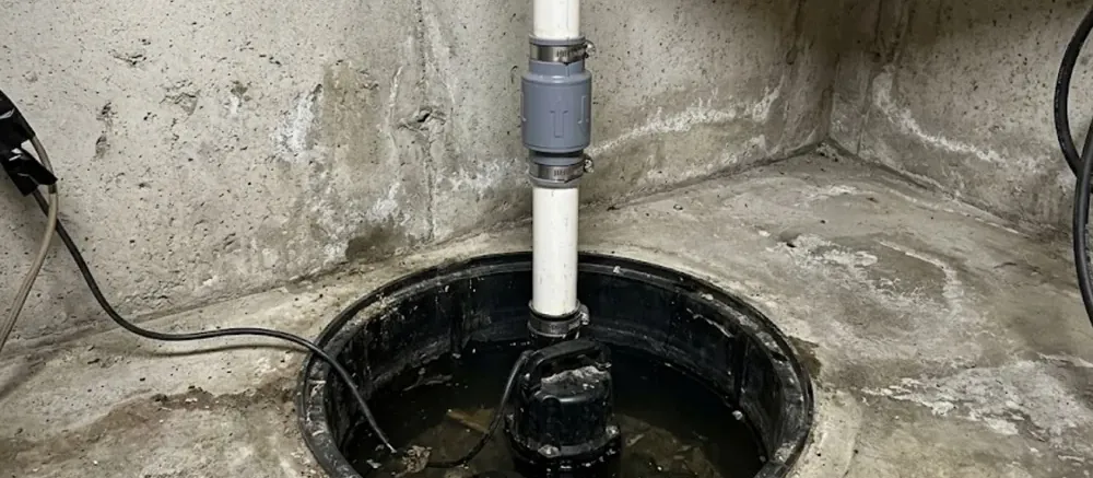 Sump pit with a pump, discharge pipe and check valve in a concrete basement corner